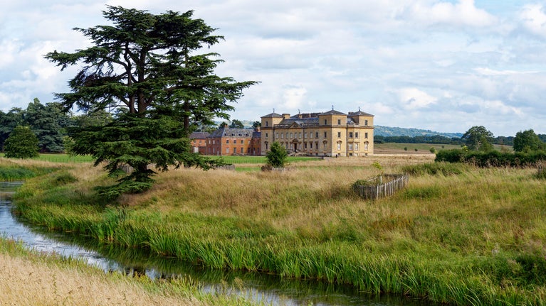 A view from 'the river' towards Croome Court on a spring day, with blue sky and lush green grass.